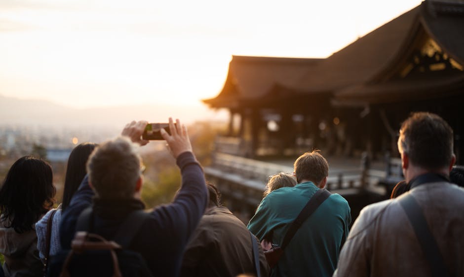 鮮やかな夕日の中、京都の美しい寺院を撮影する観光客。