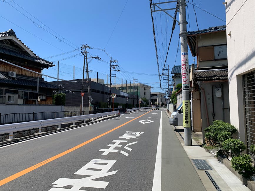 伝統的な家屋と青い空のある、日本の郊外の空いている通り。