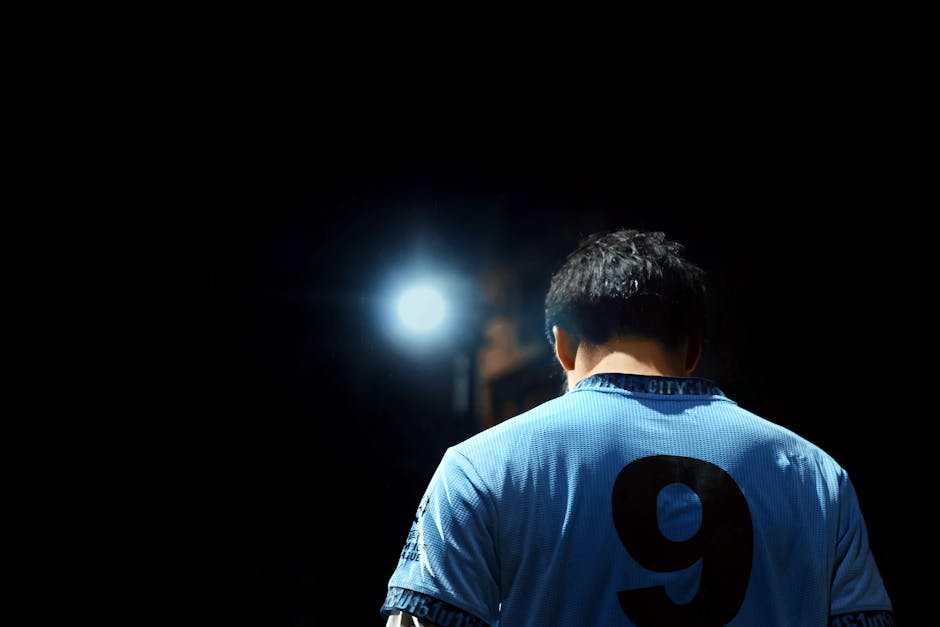 青いユニフォームに背番号9をつけたサッカー選手が、夜のスポットライトに照らされている。