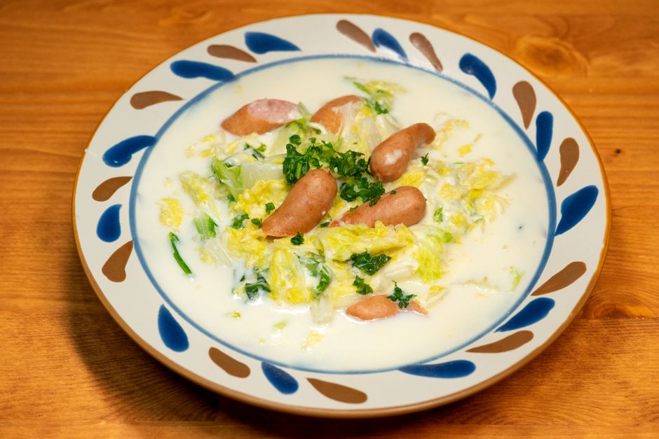 ソーセージと葉野菜をクリーミーなソースで和え、職人が手がけたお皿に盛り付けた、風味豊かなアジア料理。