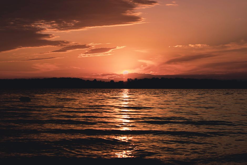 穏やかな湖面に沈む夕日が、暖かく静かな雰囲気を作り出している。