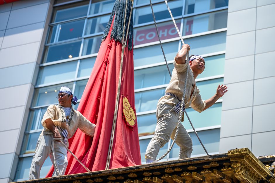 伝統的な衣装を着たパフォーマーたちが、屋外で賑やかな日本の祭りに参加しています。