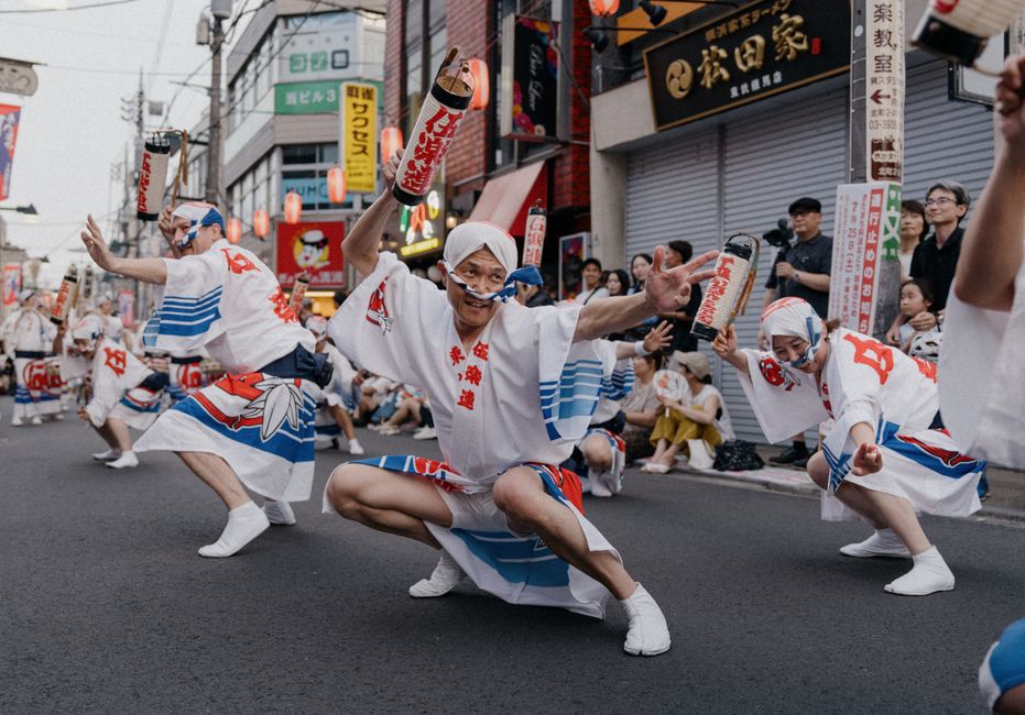 鮮やかな衣装を身にまとった日本の伝統舞踊家たちが、活気あふれる街頭祭りでパフォーマンスを披露している。